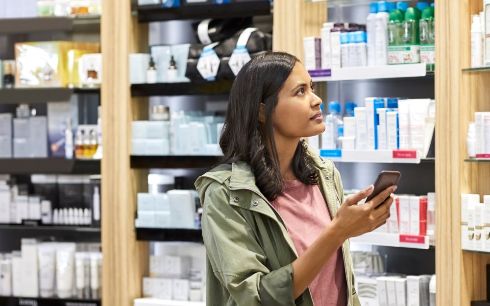 woman shopping in pharmacy with phone