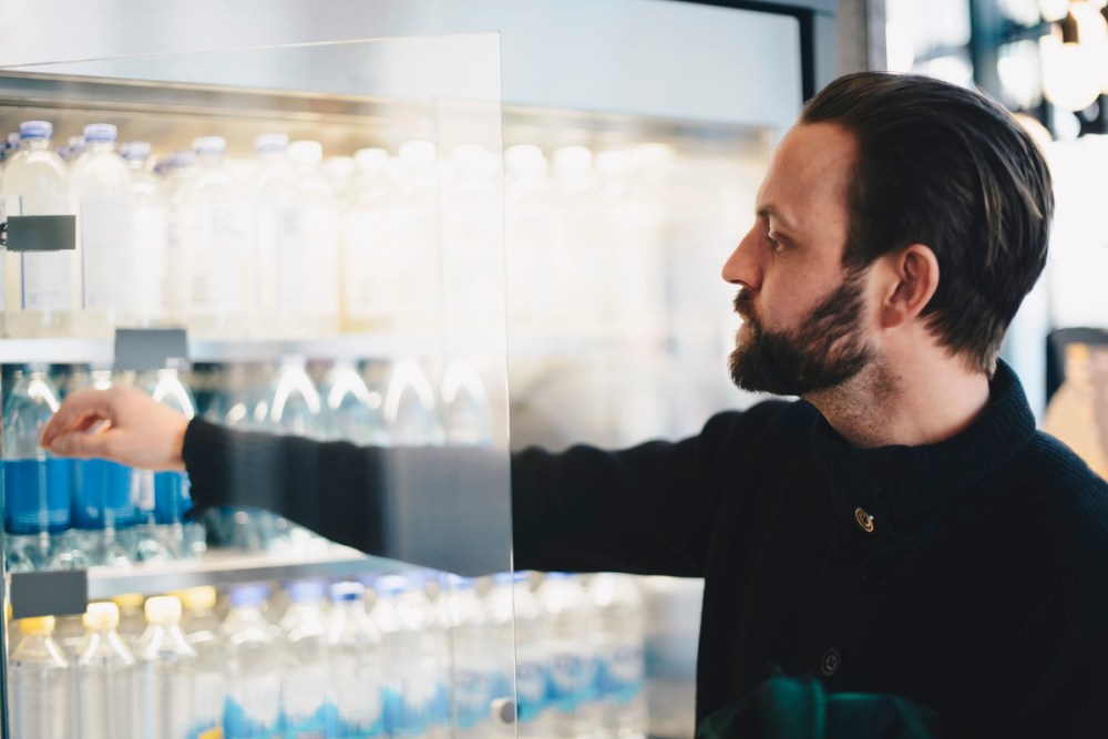 Man buying water bottle in retail store