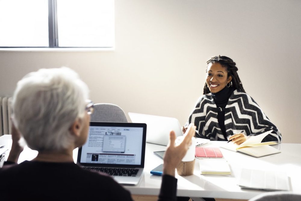 Two people sitting across from one another at a conference table