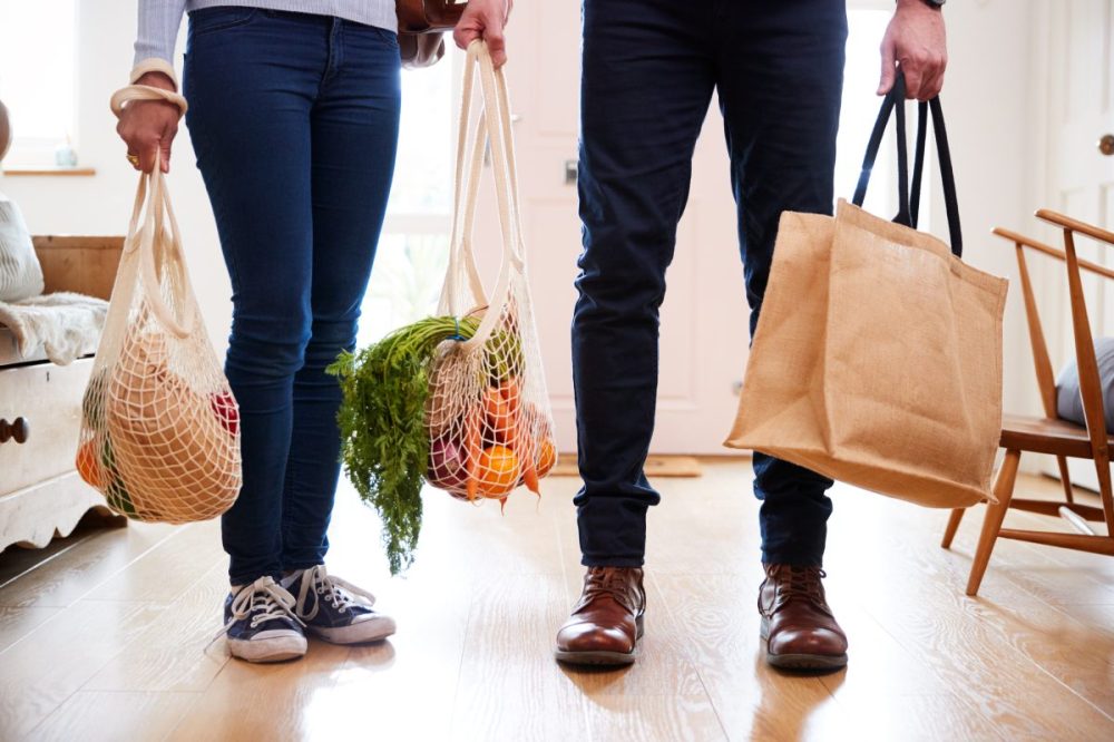 Couple holds grocery bags with plant based-dairy alternatives and produce