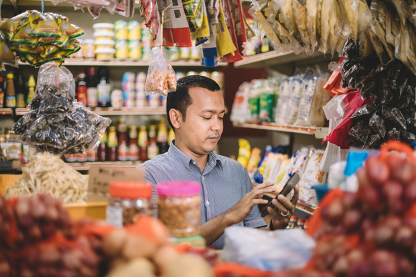 An Indian man calculating the cost for his customer's selected items