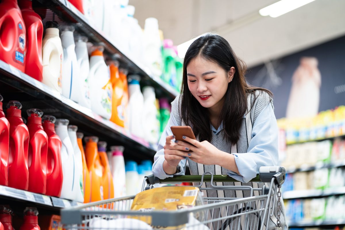 Asian Woman buys washing powder in supermarket, in the middle of her shopper journey