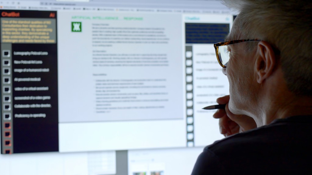 A man’s face looking into a large computer screen as type is being added to the screen by an Artificial intelligence, AI, chatbot.