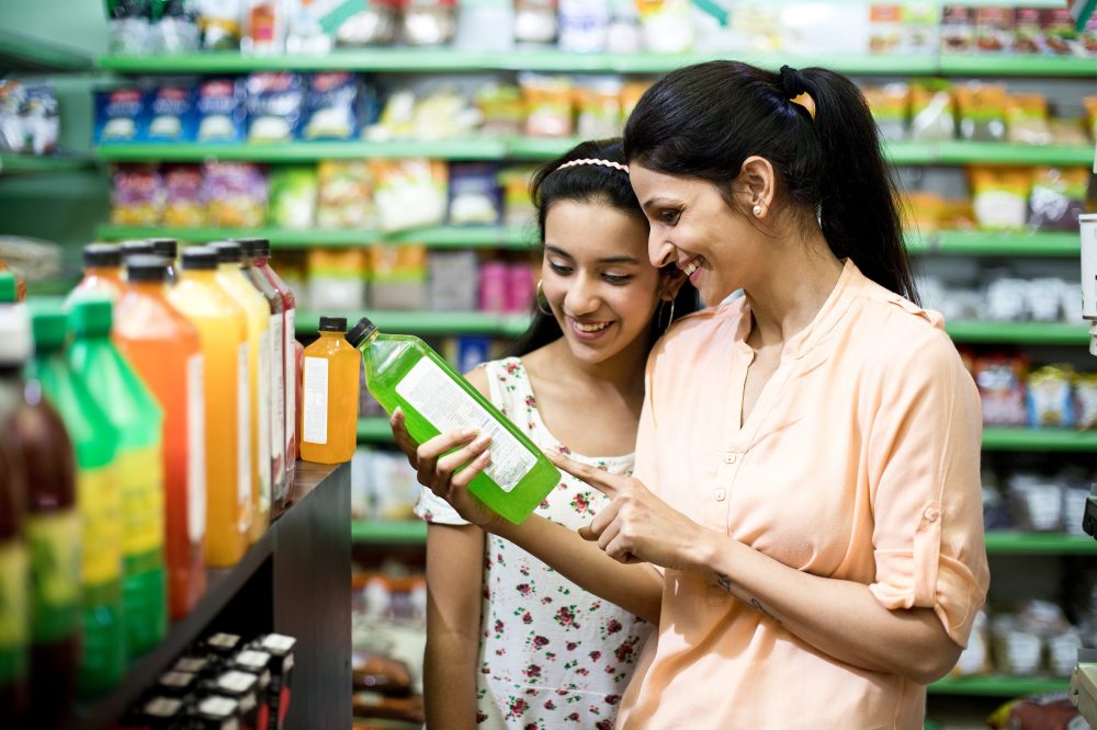 Happy mother and daughter reading product information while shopping at supermarket
