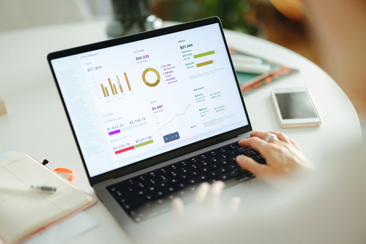 Over the shoulder view of a laptop screen showing a dashboard with charts and graphs