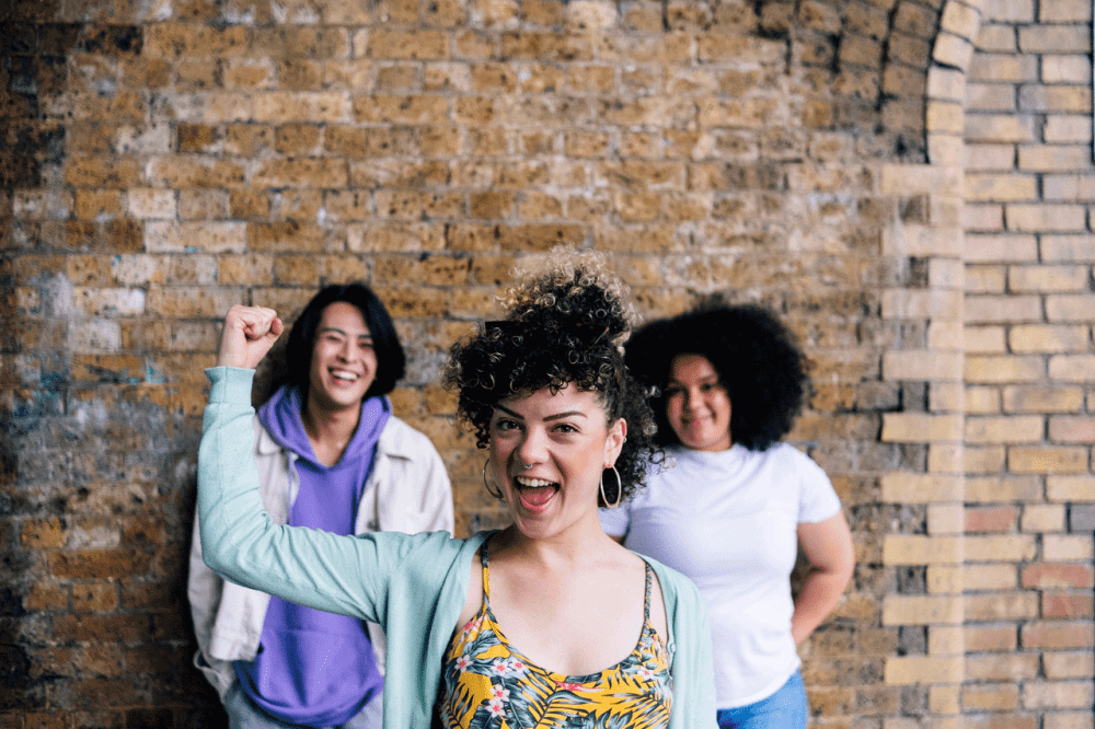 Three young people in front of a brick wall