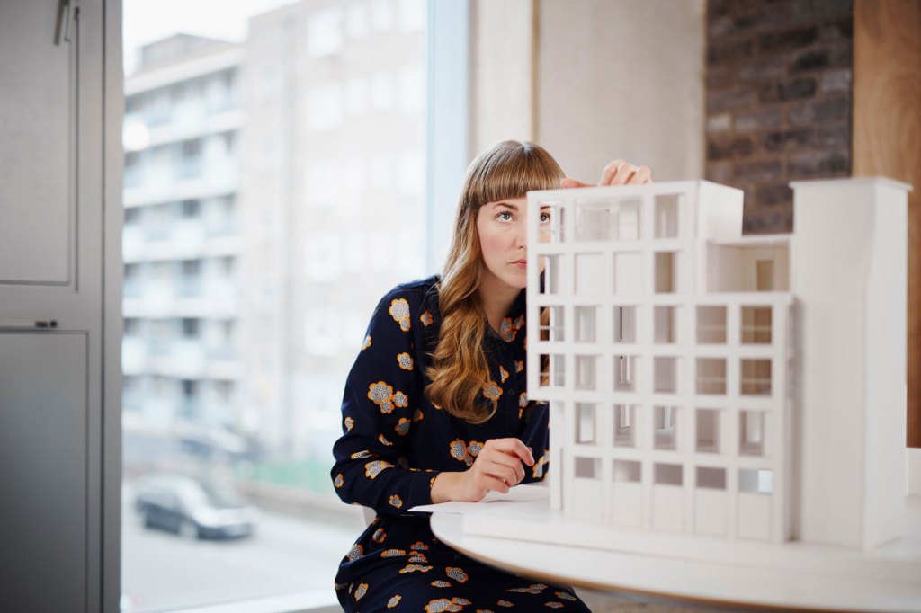 Woman working on a paper model of a building in an office setting