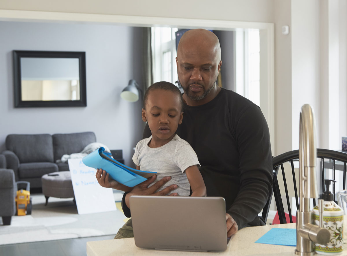 Father and son in the kitchen working on a laptop