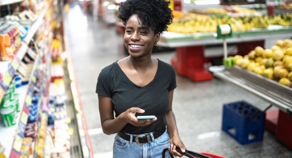 African American woman shopping with cell phone and red basket
