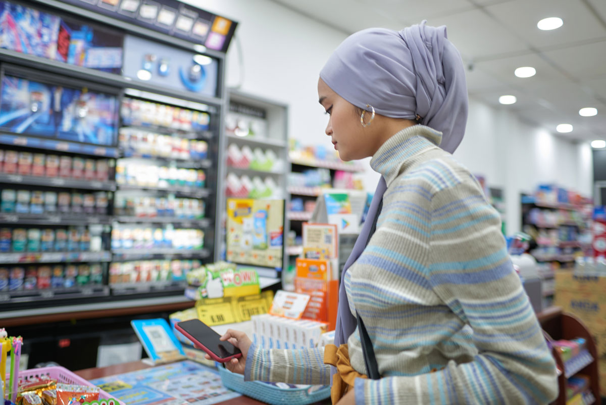 Woman with headdress in store looking at phone