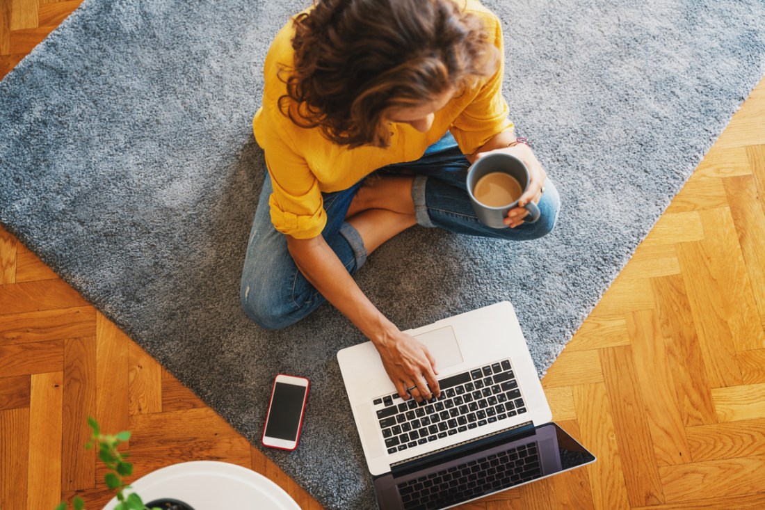 A woman shopping online while drinking coffee