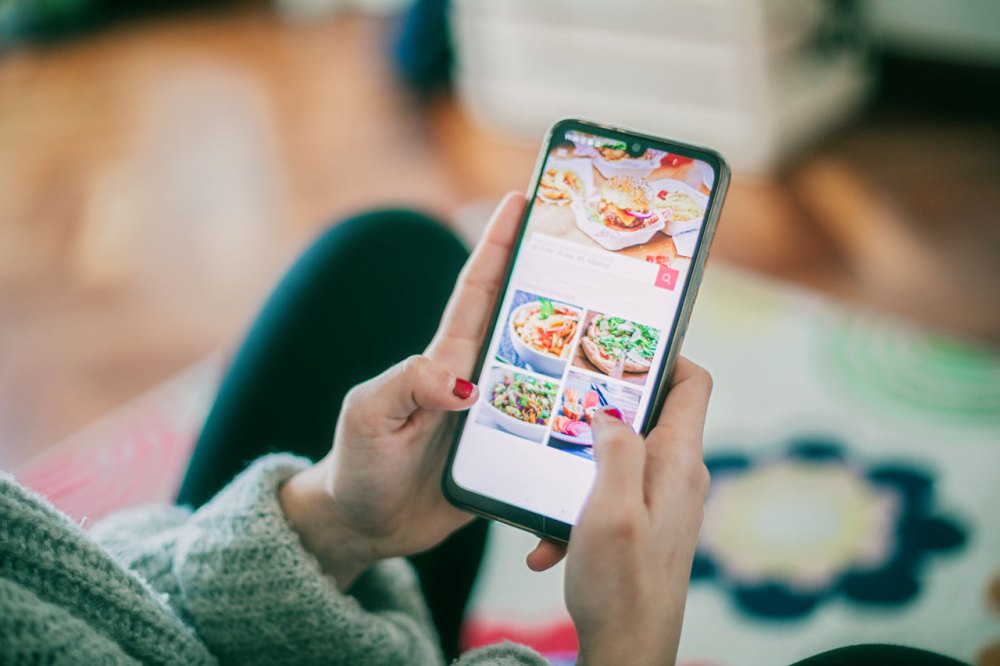Woman with green sweater and red nails shopping on her mobile device