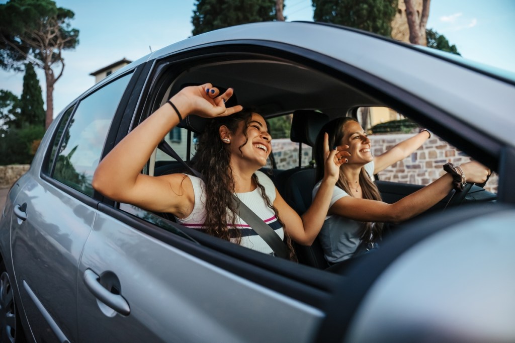 two girls driving a car with the windows down