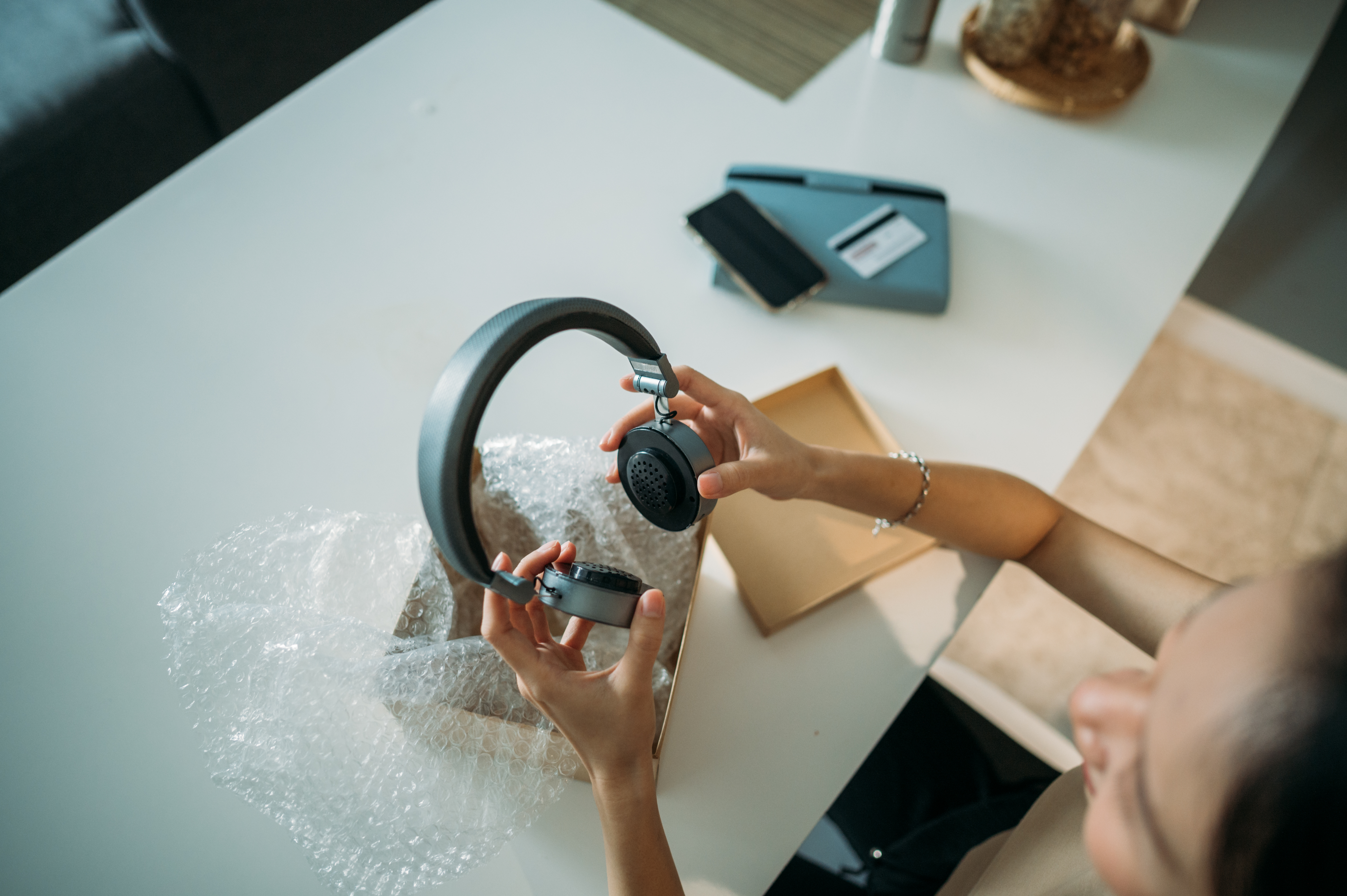 A woman unwraps her new consumer tech purchase of a pair of wireless banded headphones