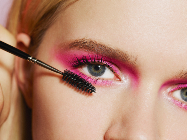 A woman applies mascara to her eyelashes