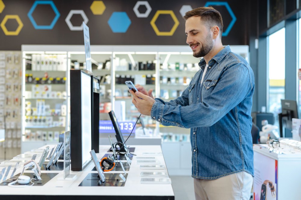 Man in a jean jacket in a mobile store looking at phones